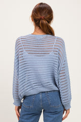 woman wearing a light blue open-knit sweater with a relaxed fit and long sleeves, styled with high-waisted jeans