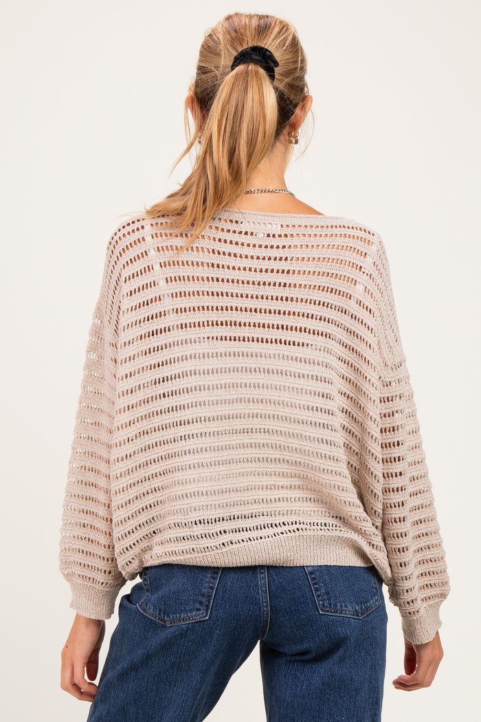 woman wearing a beige oversized knitted maternity sweater with open weave detail and back view visible