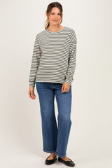 woman wearing a gray and white striped maternity top with long sleeves and blue wide-leg jeans, showing her baby bump