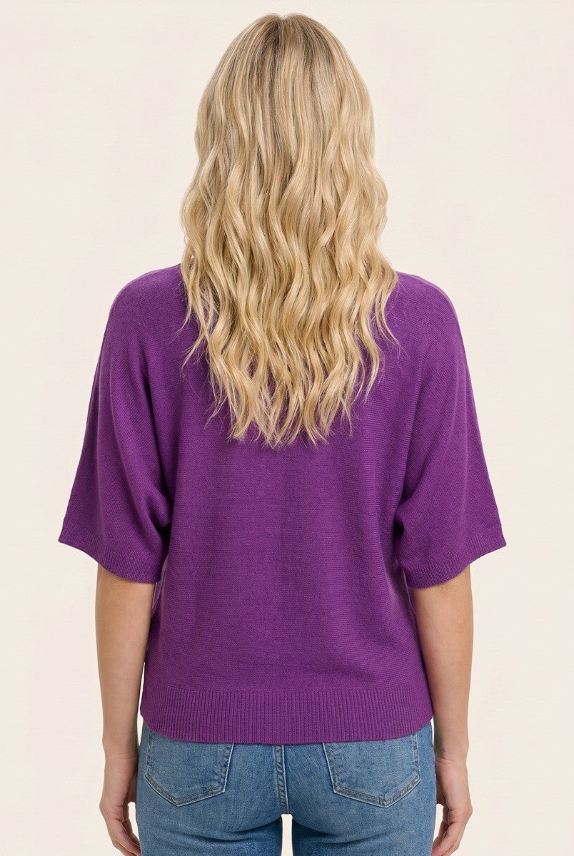 woman wearing a purple short sleeve sweater with a relaxed fit and lightweight knit, seen from the back