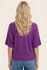 woman wearing a purple short sleeve sweater with a relaxed fit and lightweight knit, seen from the back