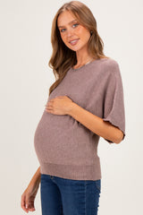 woman wearing a taupe short sleeve maternity sweater and holding her baby bump