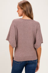 woman wearing a mauve oversized maternity sweater with short sleeves, viewed from the back