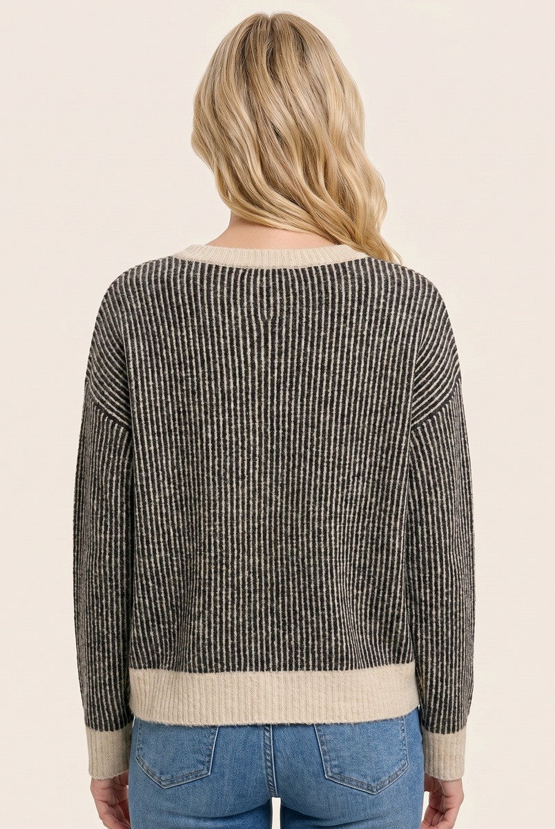 woman wearing a black and cream striped sweater viewed from the back, styled with light blue jeans