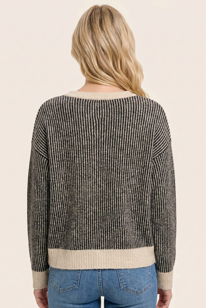 woman wearing a black and cream striped sweater viewed from the back, styled with light blue jeans