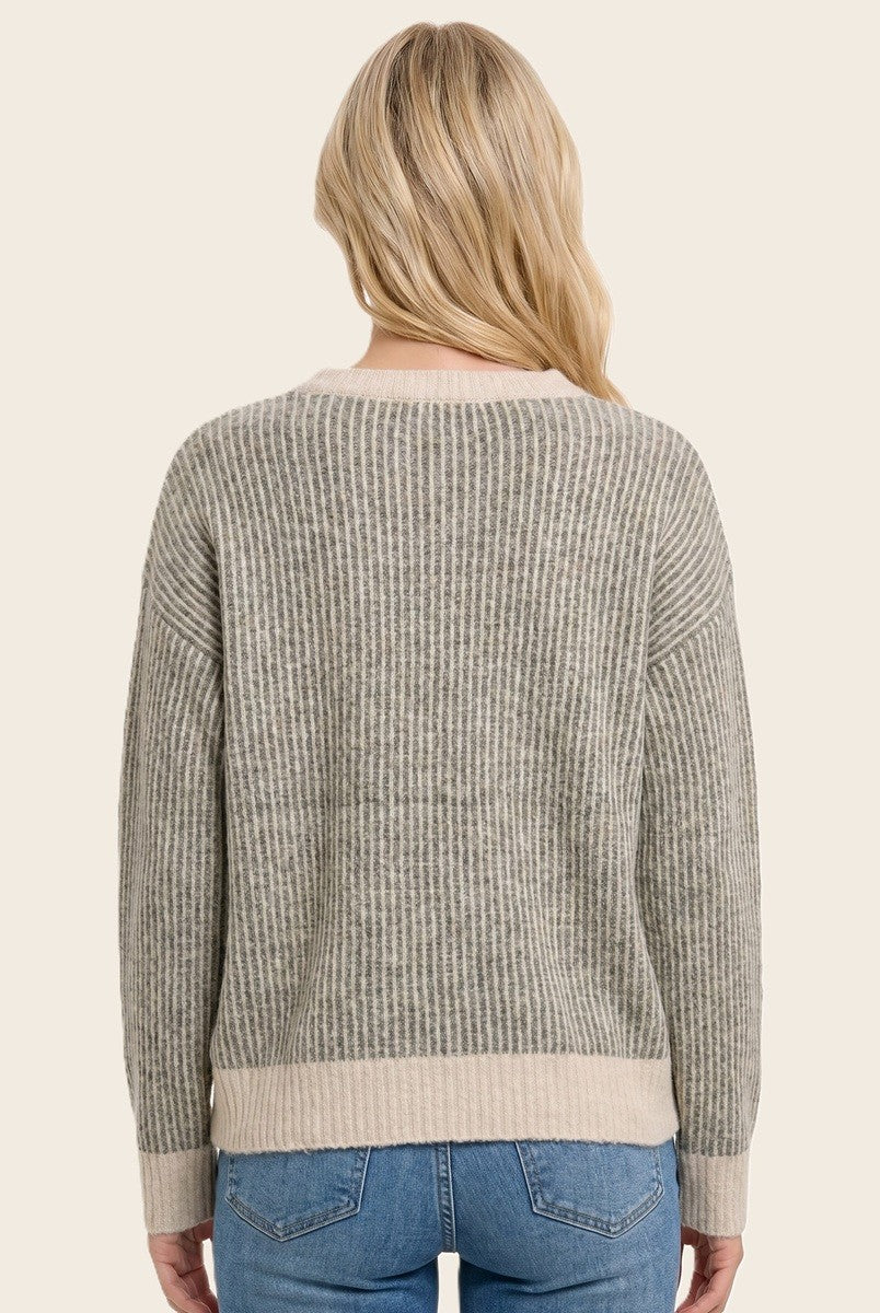 woman wearing a gray and beige striped sweater with a loose fit and long sleeves, viewed from the back