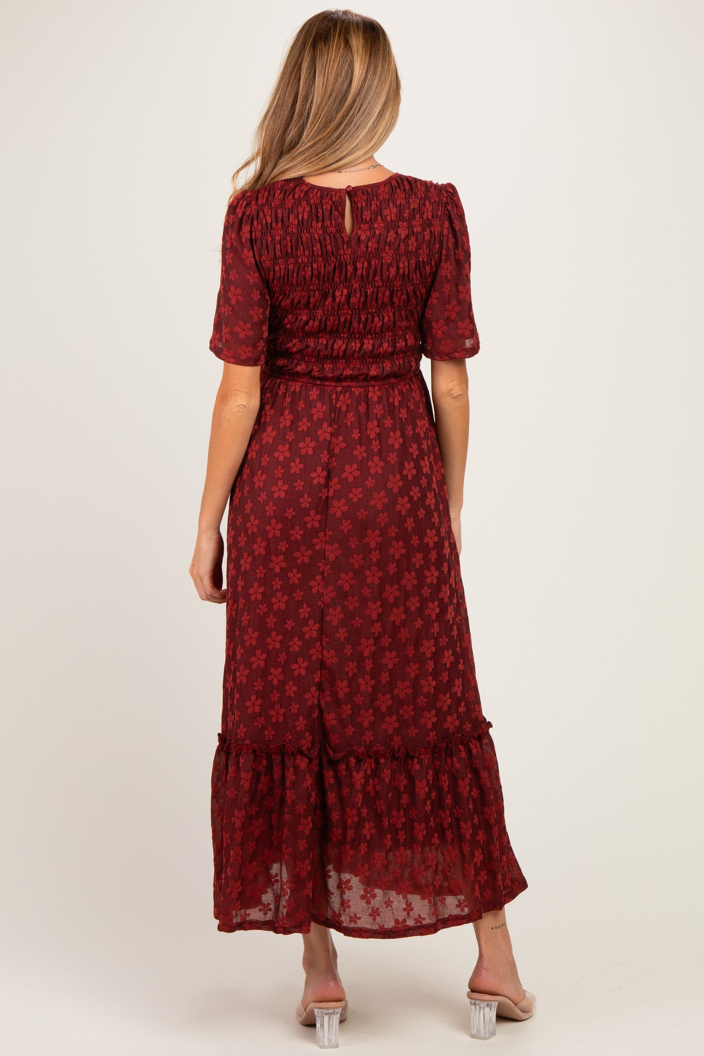 woman wearing a burgundy floral maternity maxi dress with short sleeves and smocked bodice, showing a baby bump