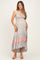 woman wearing a light blue floral print maternity dress with a high-low hem and a baby bump visible