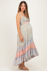 woman wearing a light blue floral maternity dress with adjustable straps and a ruffled hem, showcasing her baby bump