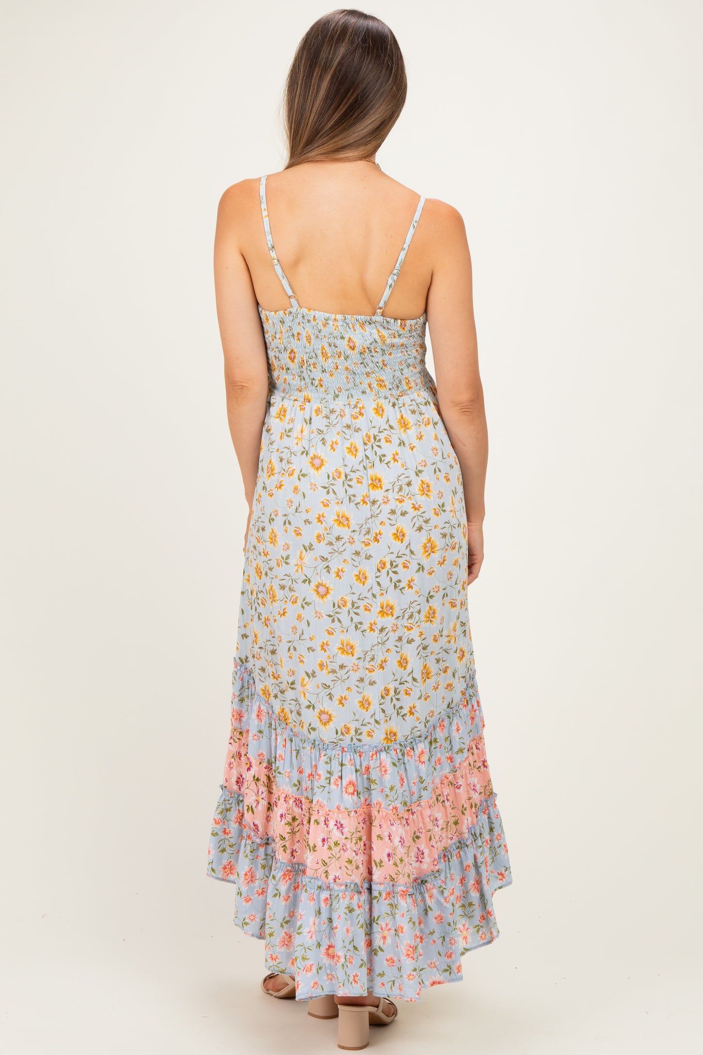woman wearing a light blue maternity maxi dress with floral prints and a ruffled hem, showing her back