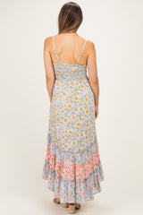 woman wearing a light blue maternity maxi dress with floral prints and a ruffled hem, showing her back