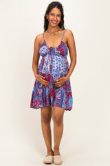 woman wearing a colorful patterned maternity dress with a fitted bodice and flowy skirt, gently holding her baby bump