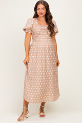 woman wearing a polka dot maternity dress with puff sleeves and a fitted bodice, smiling against a neutral background