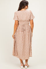 woman wearing a beige maternity dress with white polka dots and a smocked waist, viewed from the back