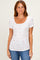 woman wearing a white short sleeve scoop neck top with a pink floral print and gathered sides paired with blue jeans
