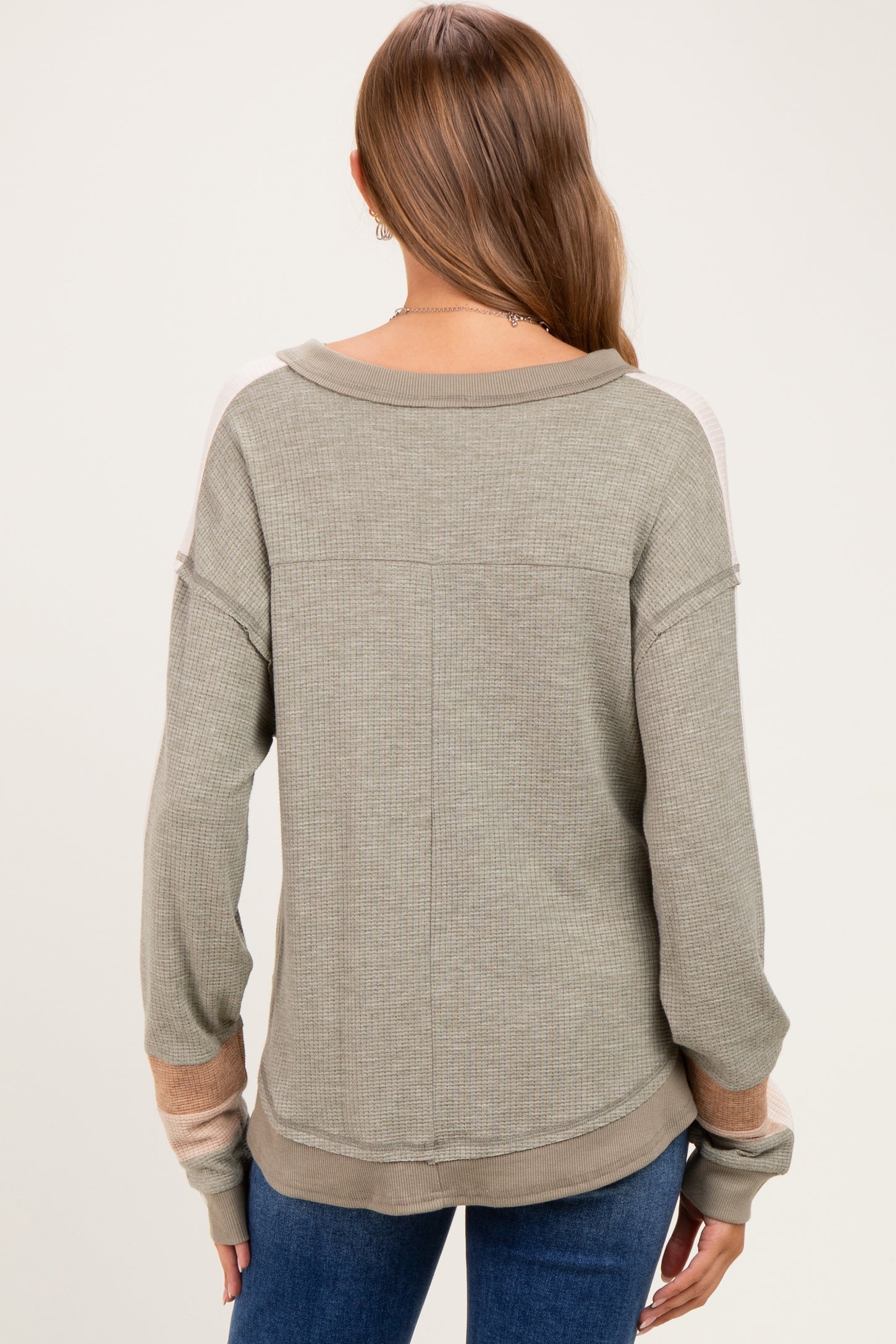woman wearing a green long sleeve maternity top with stripes on the sleeves, viewed from the back