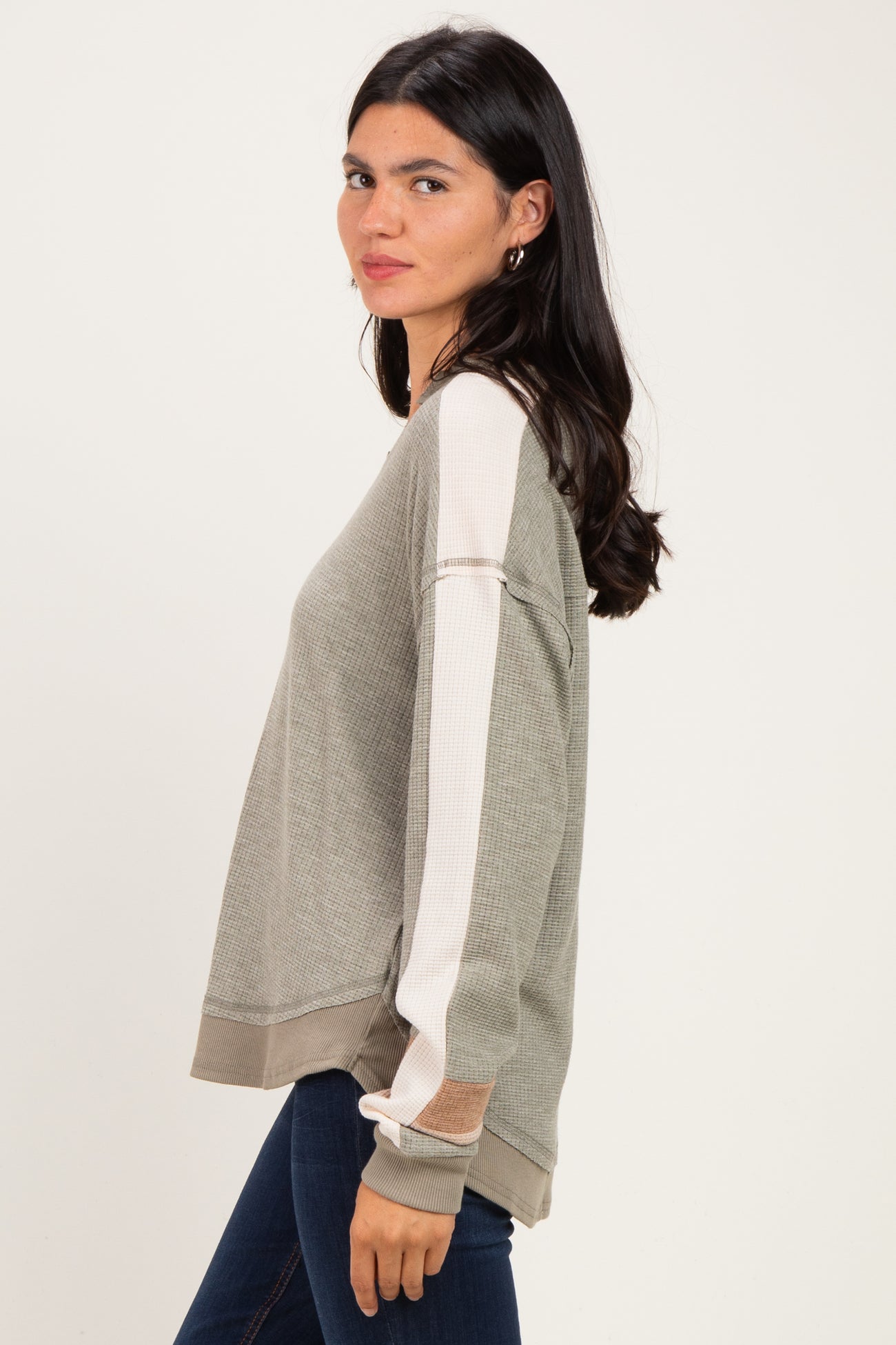 woman wearing a gray and cream colorblock long sleeve sweater with ribbed details and a relaxed fit