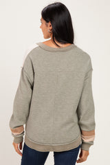 woman wearing a light green oversized sweater with color block sleeves and a relaxed fit, viewed from the back