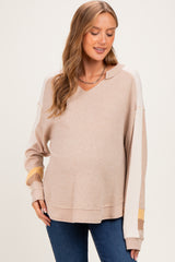 woman wearing a beige maternity wear v-neck sweater with taupe and mustard stripes and a visible baby bump