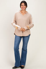 woman wearing a beige oversized long sleeve sweater with color block details and flared jeans