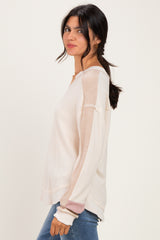 woman wearing a cream long sleeve top with textured fabric and color block sleeves, styled with light blue jeans