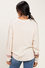 woman wearing a beige color block long sleeve top with a relaxed fit and ribbed texture, seen from the back