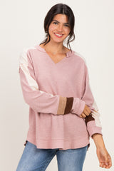 woman wearing a pink v-neck oversized sweater with colorblock sleeves and smiling at the camera