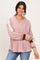 woman wearing a pink v-neck oversized sweater with colorblock sleeves and smiling at the camera