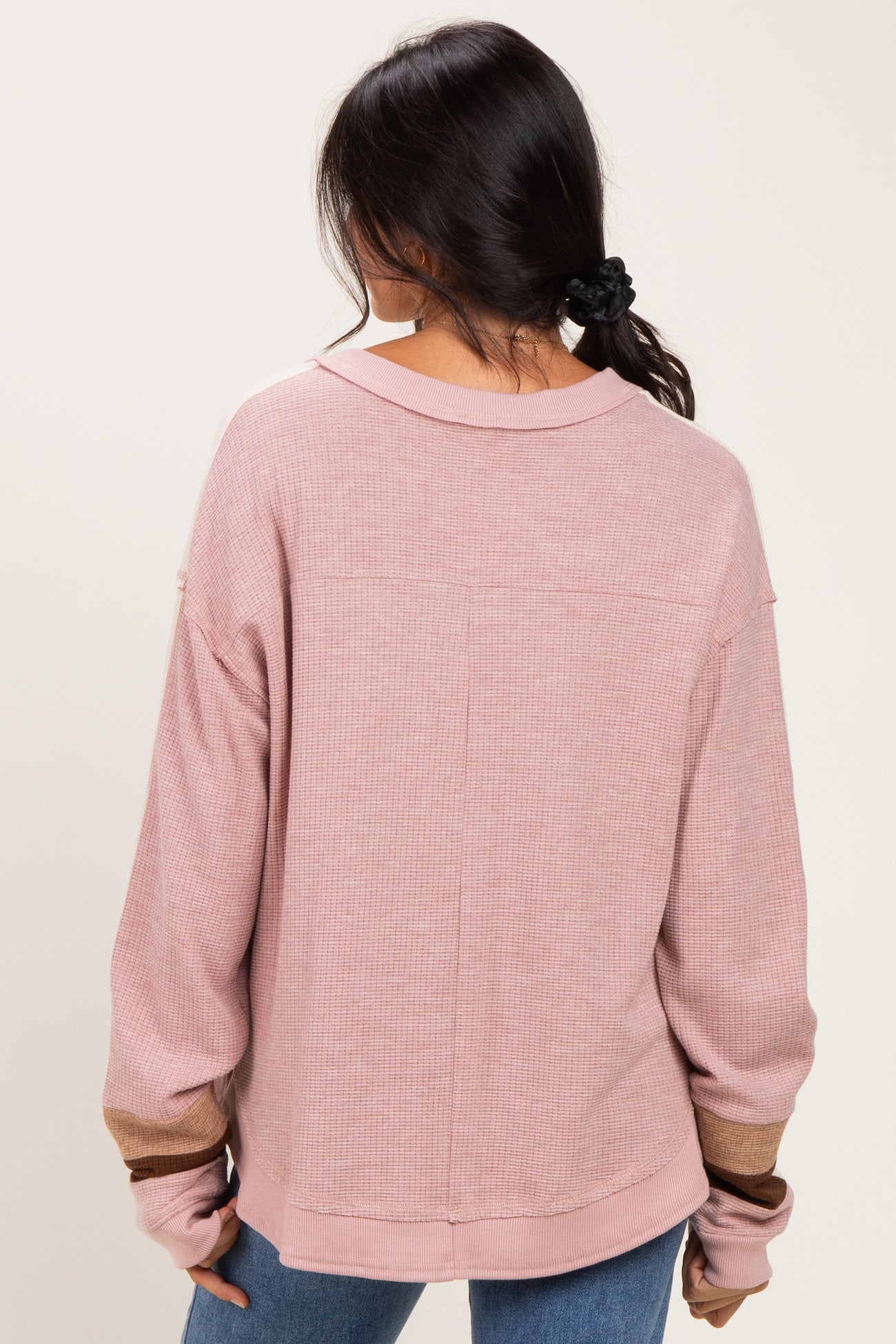 woman wearing a pink oversized cardigan with long sleeves and a relaxed fit, showing the back view