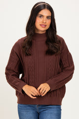 woman wearing a brown cable knit sweater with a high neckline and relaxed fit, paired with blue jeans