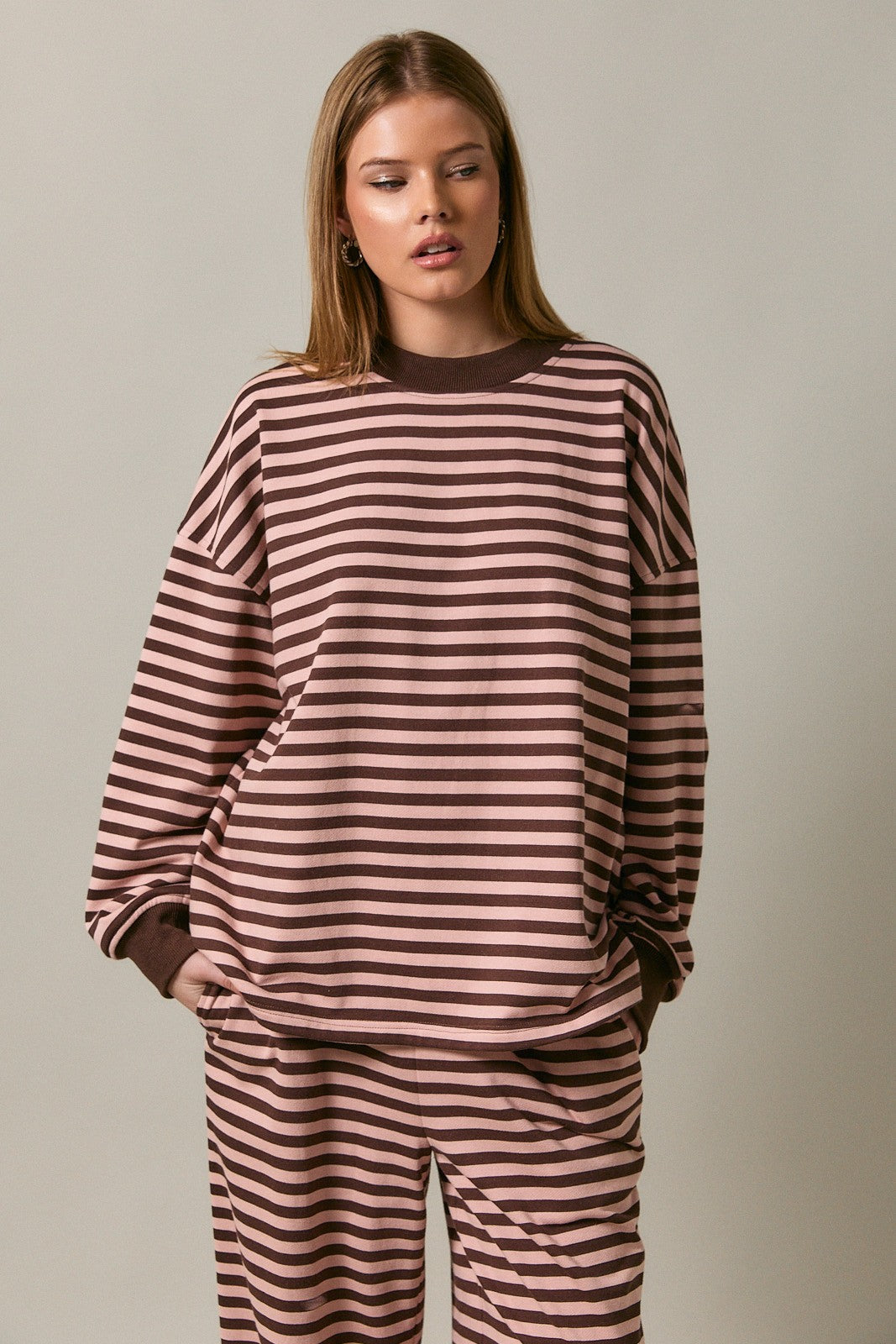 woman wearing a brown and pink striped oversized sweatshirt with long sleeves and a round neckline