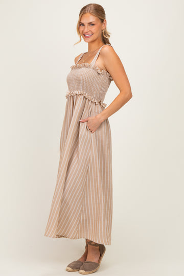 woman wearing a beige and white striped maxi dress with a smocked bodice and ruffled straps, posing with hands in pockets