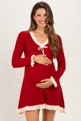 woman wearing a red ribbed maternity dress with cream-colored trim and a tie detail, showing her baby bump