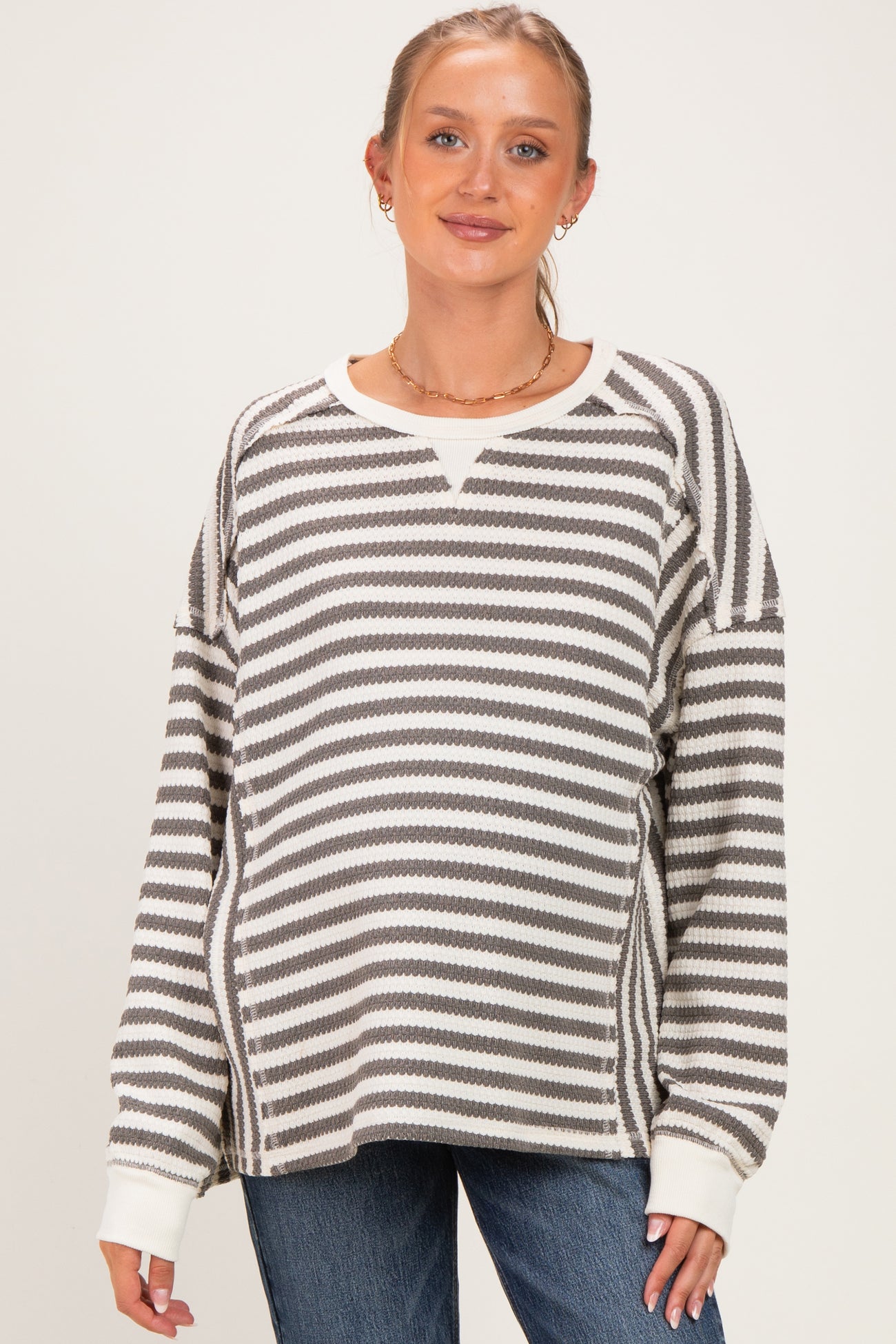 woman wearing a striped maternity sweater in gray and white with a relaxed fit and v-neck design