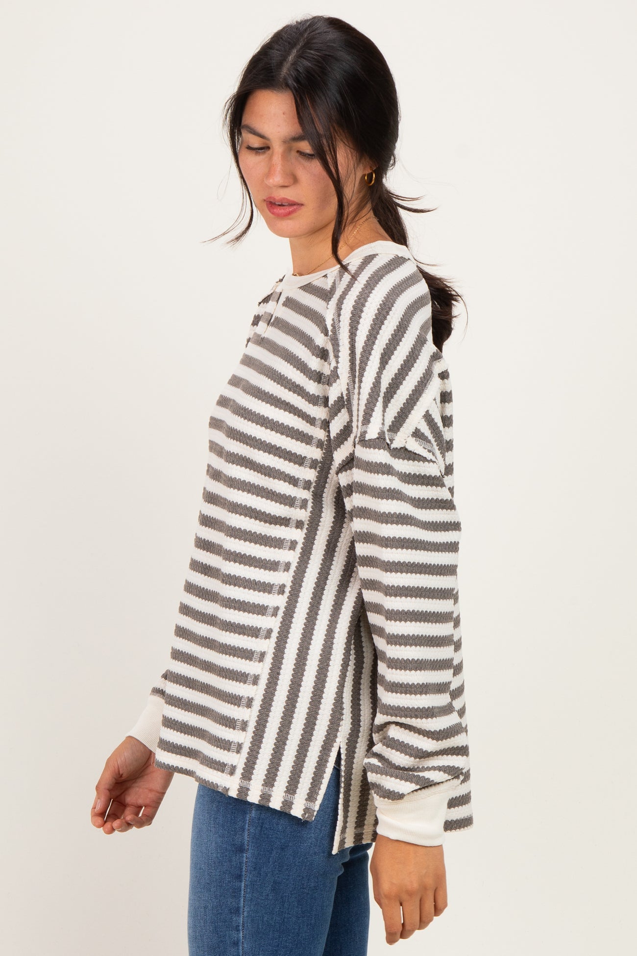 woman wearing a gray and white striped long sleeve top with side slits and a relaxed fit