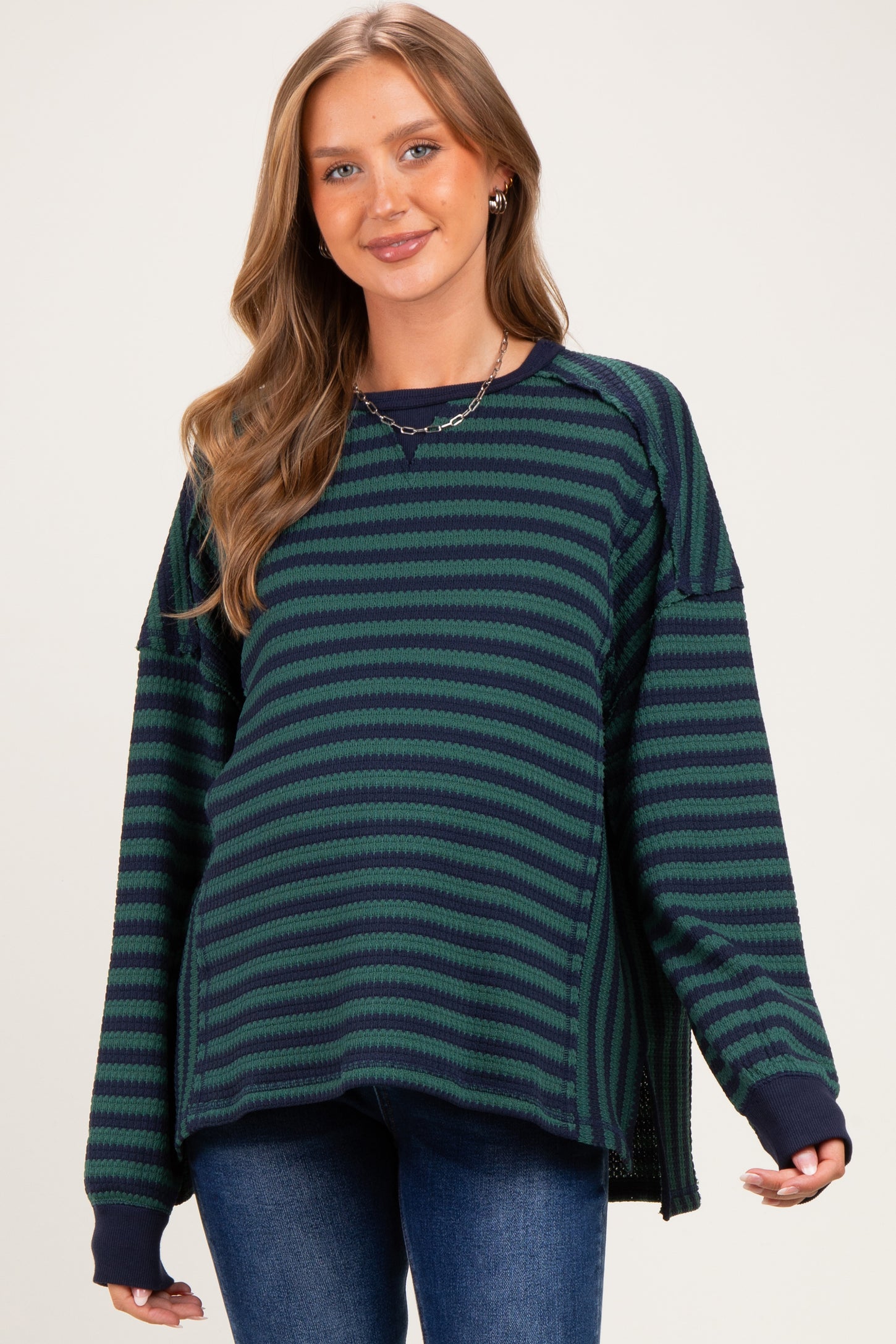 woman wearing a striped green and navy maternity sweater with a relaxed fit and side slits