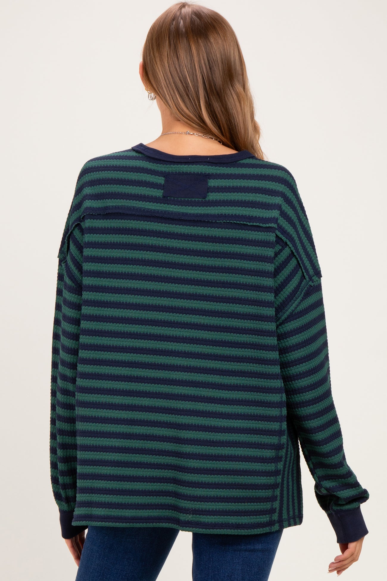 woman wearing a green and navy striped maternity sweater, showing the back view with a relaxed fit
