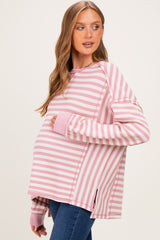 woman wearing a pink and white striped maternity sweater with a visible baby bump and relaxed fit