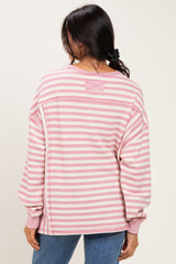 woman wearing a pink and white striped oversized sweater with long sleeves, seen from the back