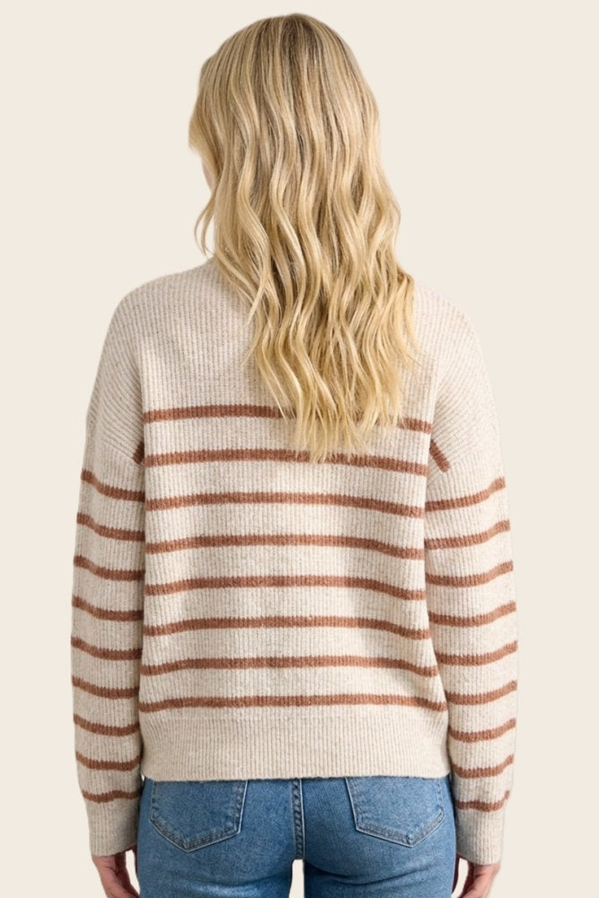 woman wearing a cream striped sweater with rust-colored stripes, styled with medium blue jeans, viewed from the back