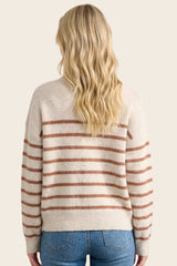 woman wearing a cream striped sweater with rust-colored stripes, styled with medium blue jeans, viewed from the back