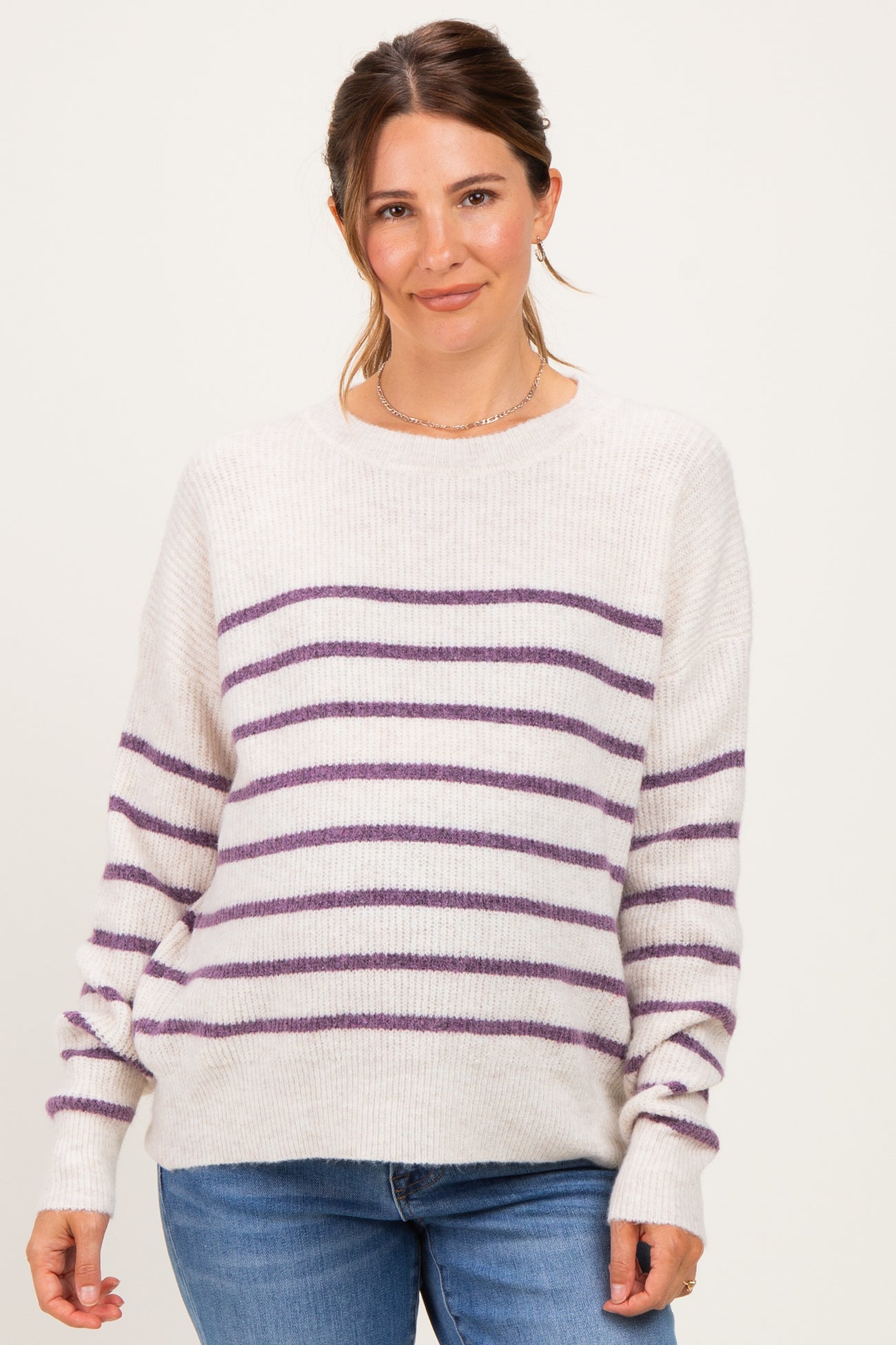 woman wearing a cream and purple striped maternity sweater with a relaxed fit and long sleeves