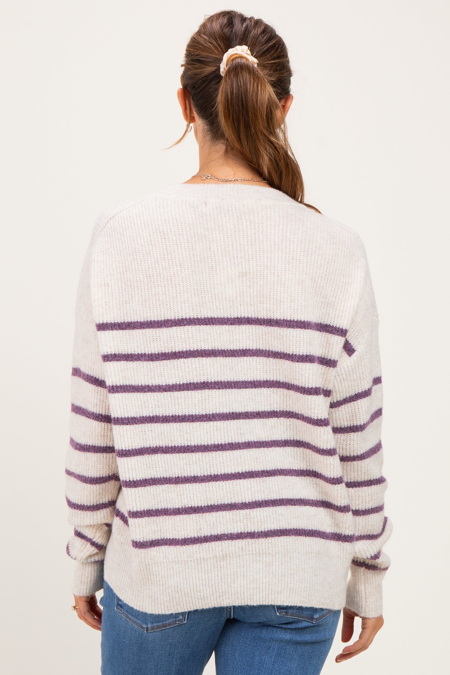 woman wearing a striped cream and purple maternity sweater, shown from the back with a relaxed fit
