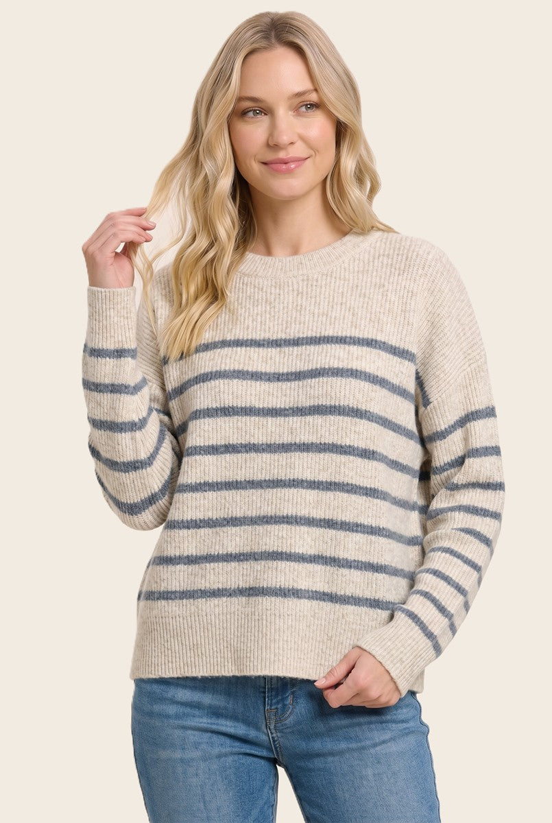 woman wearing a cream and navy striped sweater with long sleeves and a round neckline, paired with blue jeans