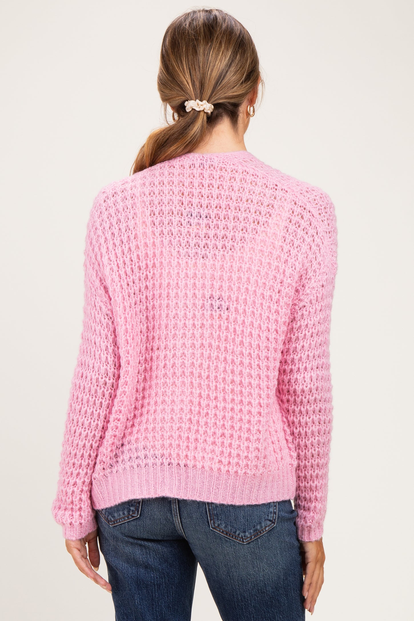 woman wearing a pink knitted maternity sweater with a relaxed fit and back view, paired with jeans