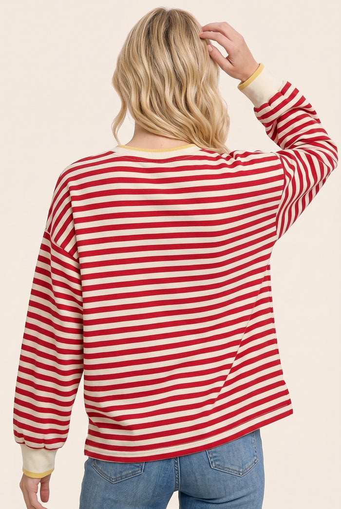 woman wearing a red and white striped long sleeve shirt with yellow cuffs, showing the back view