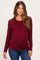 woman wearing a burgundy long sleeve maternity top and showing her baby bump