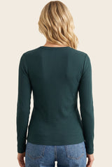 woman wearing a dark green long sleeve ribbed top, viewed from the back, paired with light blue jeans