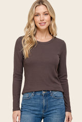 woman wearing a dark brown long sleeve ribbed top with a round neckline and casual blue jeans