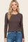 woman wearing a dark brown long sleeve ribbed top with a round neckline and casual blue jeans